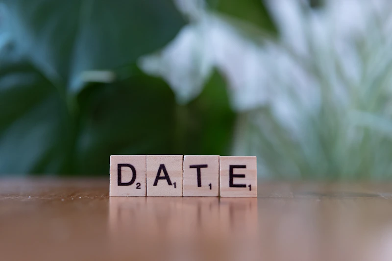 A scrabble block spelling the word date on a table