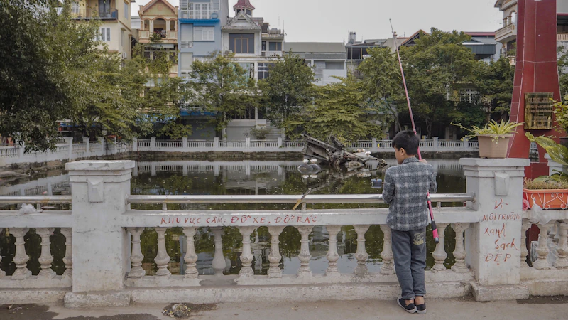 man in white and blue plaid dress shirt and gray pants standing on white concrete bridge